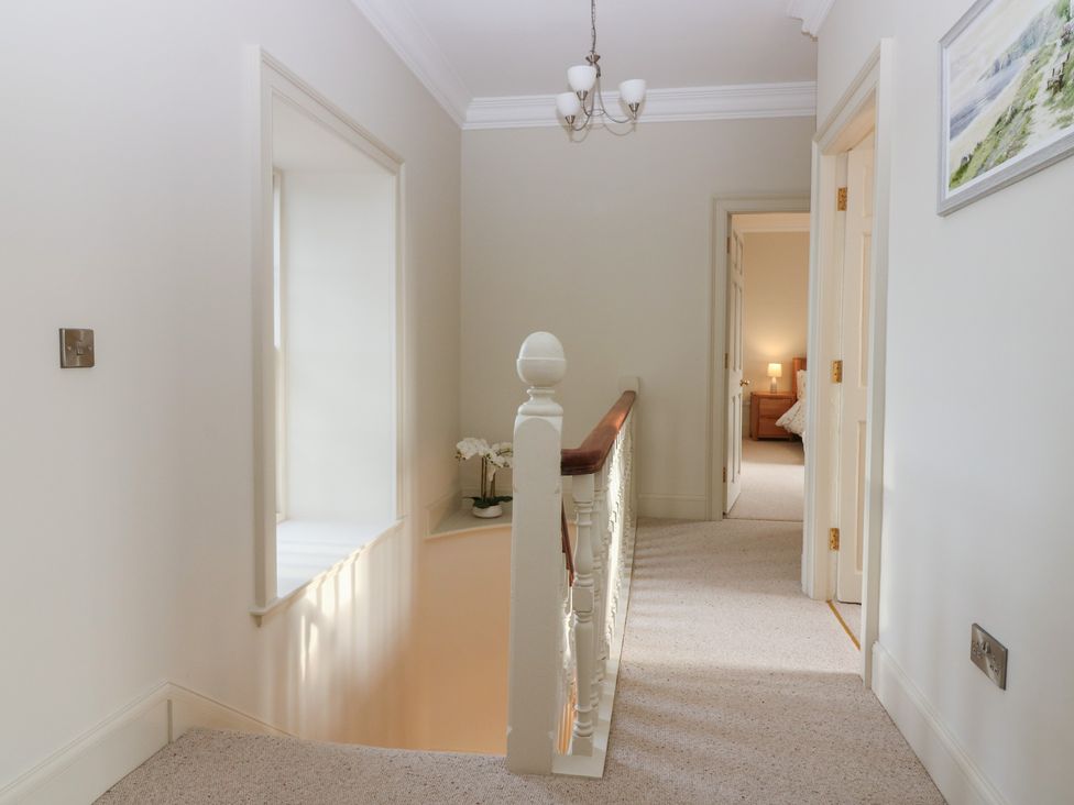 A hallway with a railing and light fixture at Balmashanner Farmhouse in Forfar