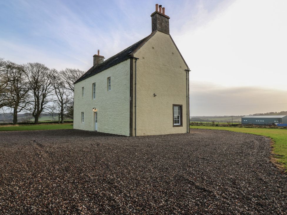 A house with a gravel driveway and trees at Balmashanner Farmhouse Forfar