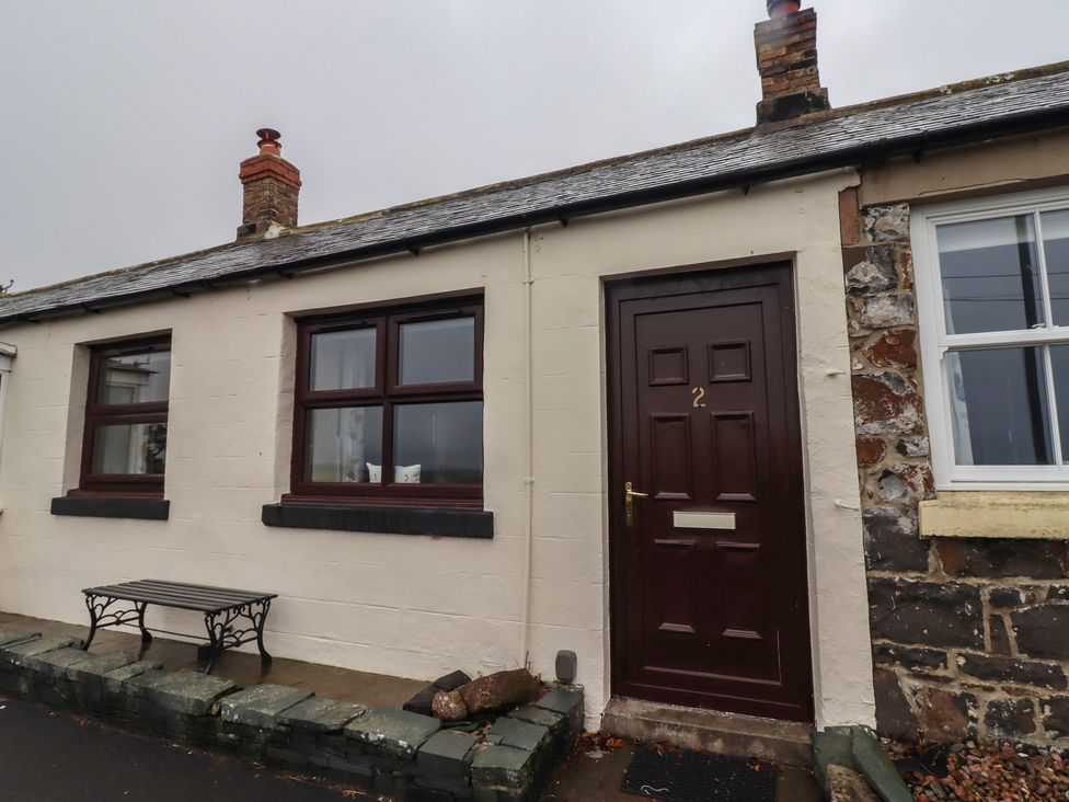 An outdoor view of a cottage with a bench and door at Sunny Brae in Alnwick