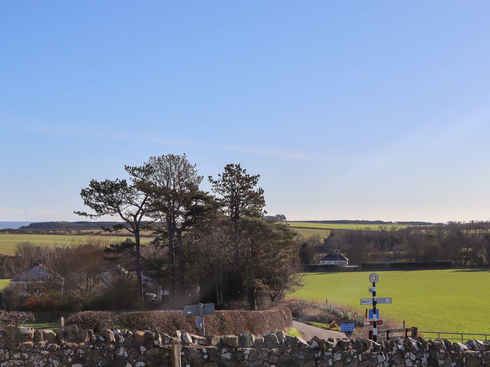 A view of trees and a field with signposts at 2 Sunny Brae in Embleton