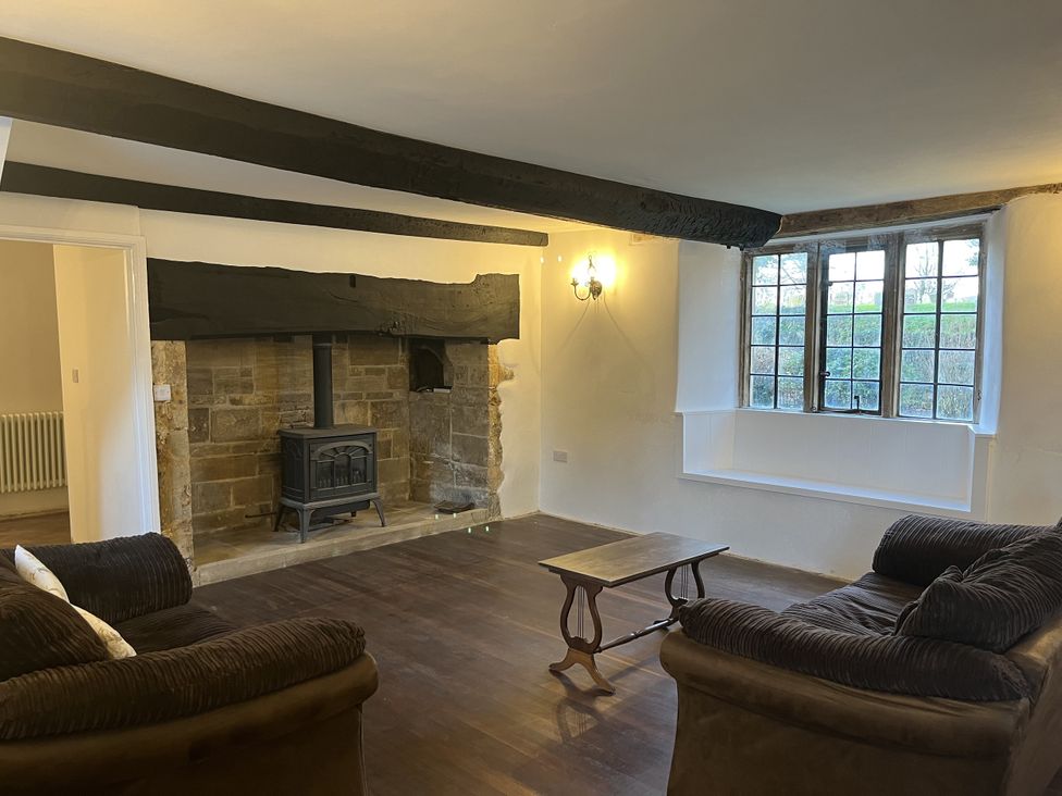 A living room with a wood stove and two sofas at Manor Cottage in Ilminster