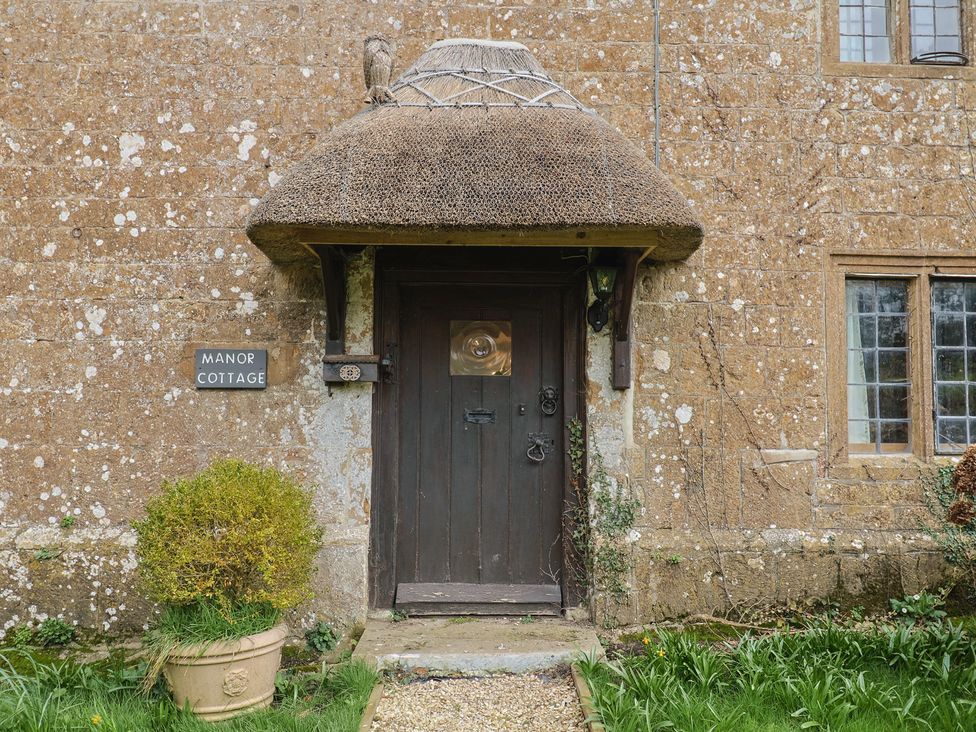 The entrance of Manor Cottage with a thatch roof and front door in Kingstone near Ilminster