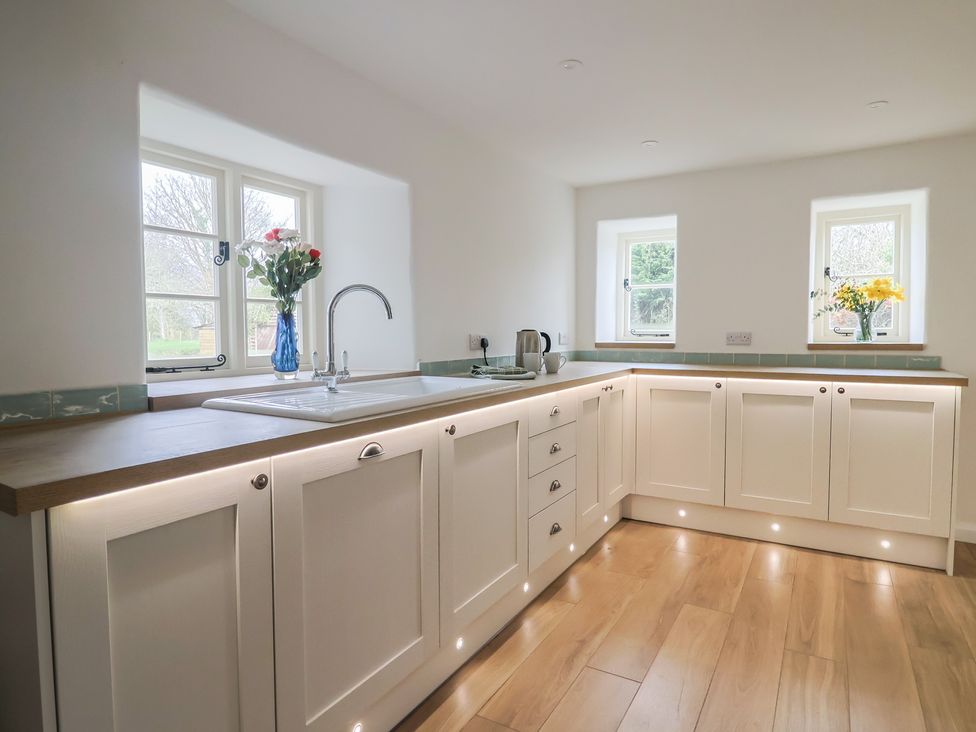 A kitchen with a sink and flowers in a vase at Manor Cottage Kingstone near Ilminster