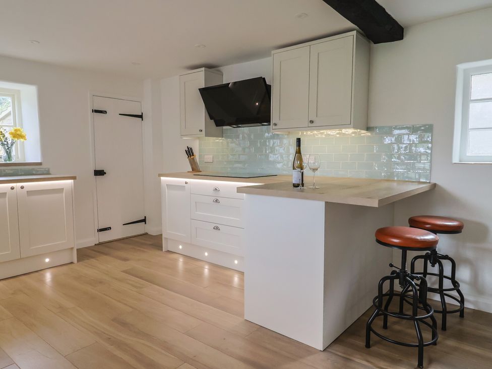 A kitchen with a countertop and bar stools at Manor Cottage Kingstone near Ilminster