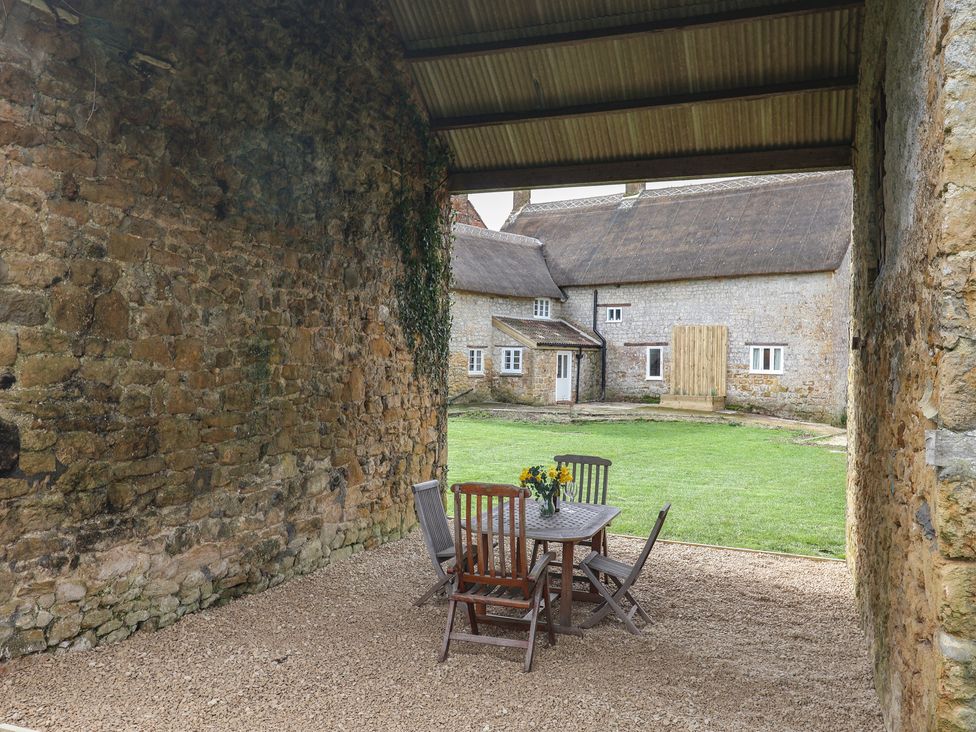 An outdoor area with a table and chairs near a stone wall at Manor Cottage in Kingstone near Ilminster