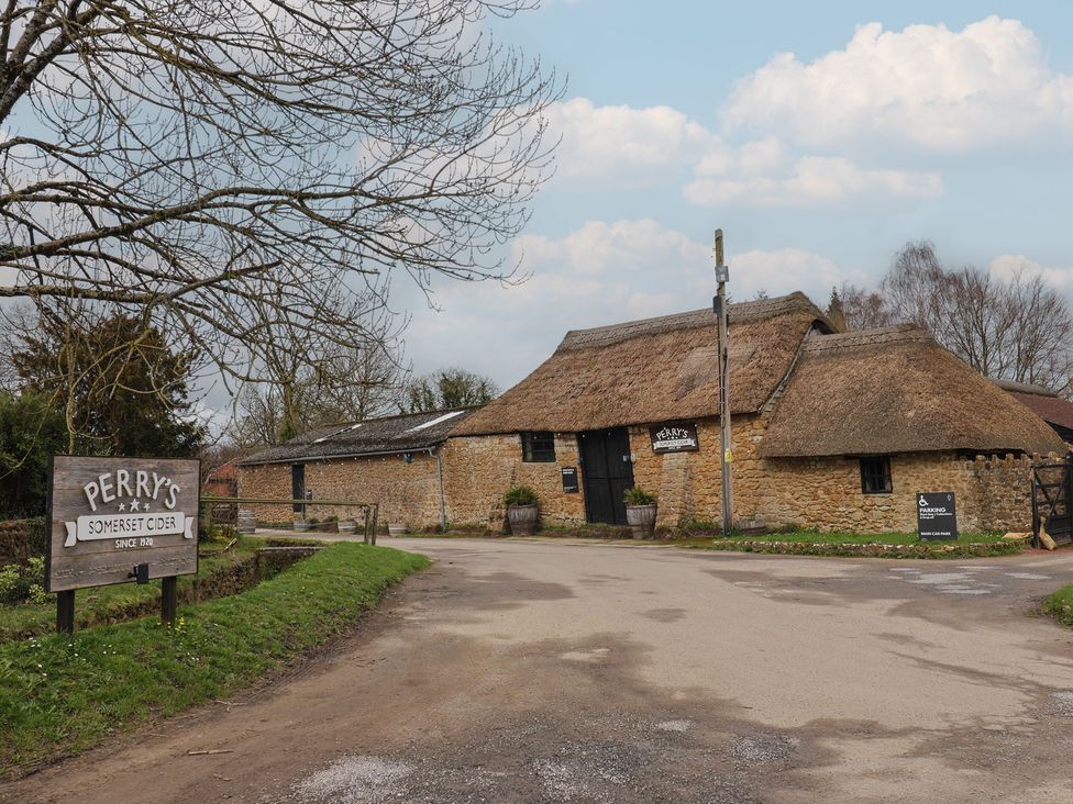 A building with a thatched roof and sign at Perry's Somerset Cider in Kingstone near Ilminster