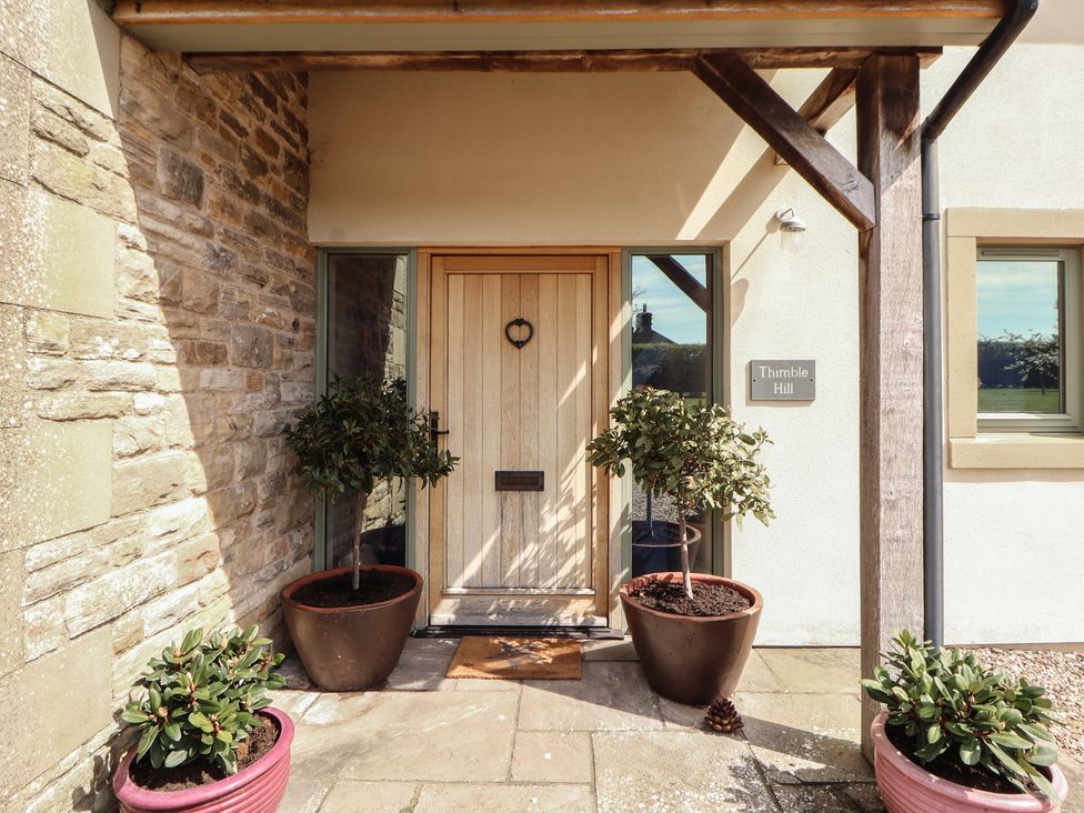 An entrance with a wooden door and planters at Thimble Hill Near Armathwaite