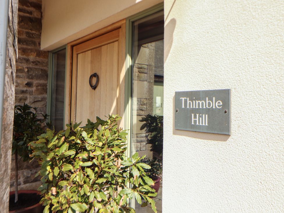 An entrance with a wooden door and a house number sign at Thimble Hill near Armathwaite