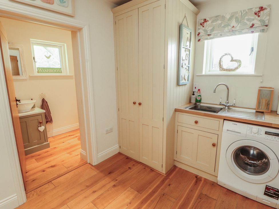 A washroom with a sink and washing machine at Thimble Hill Near Armathwaite