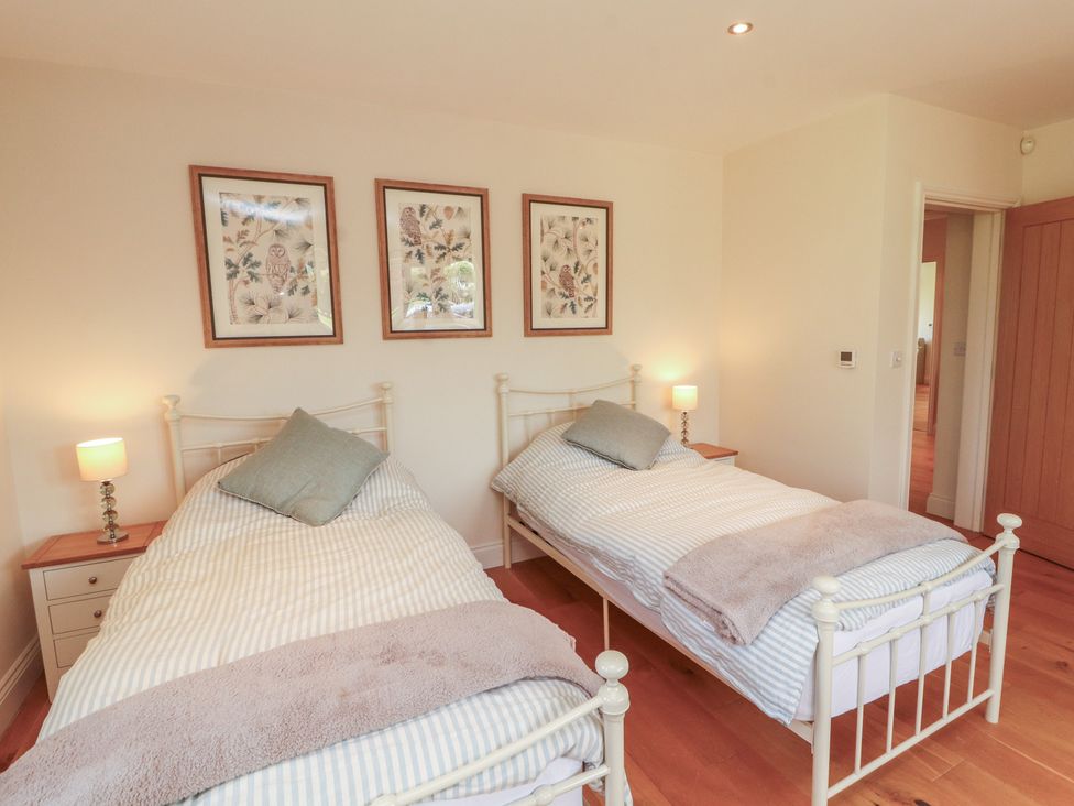 A bedroom with two single beds and three framed pictures at Thimble Hill near Armathwaite
