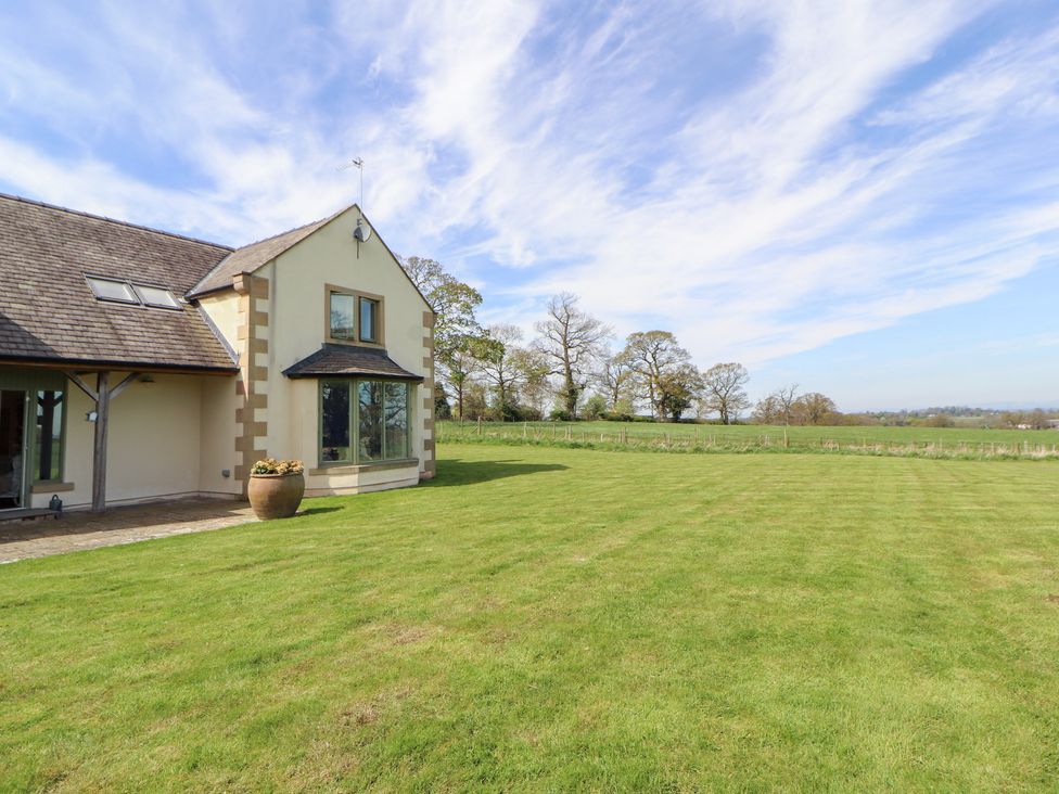 An exterior view of a house with a lawn and trees at Thimble Hill near Armathwaite