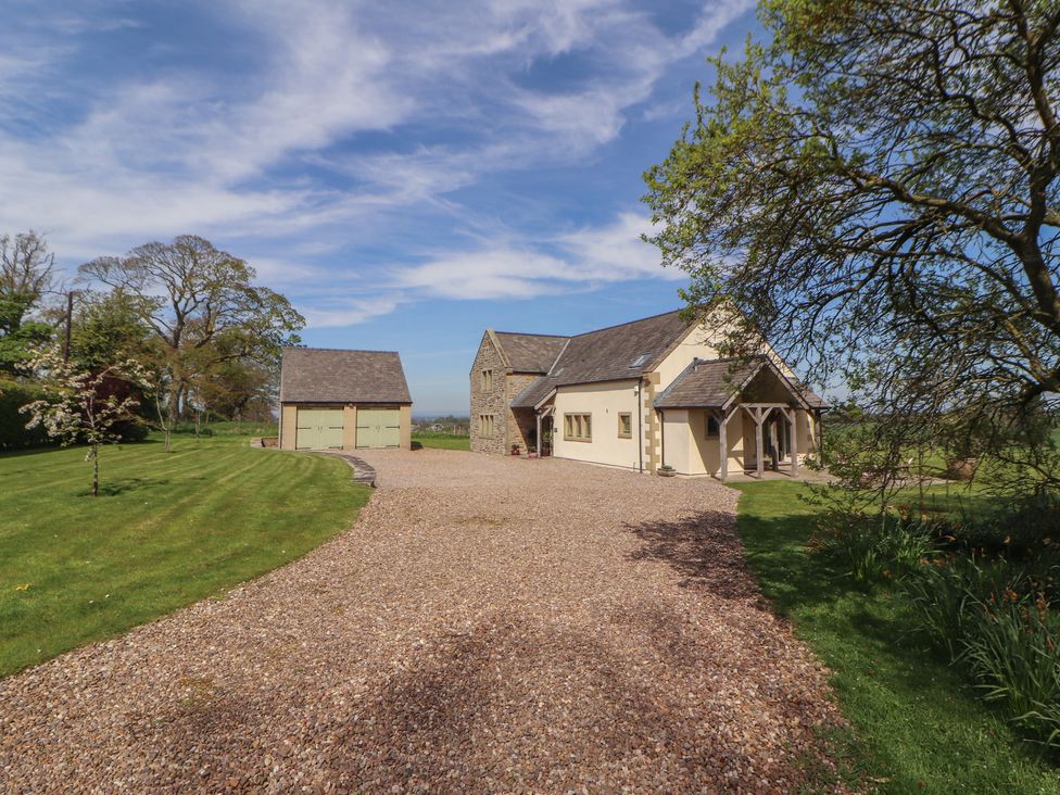An exterior view of a house and garage with a gravel driveway at Thimble Hill near Armathwaite