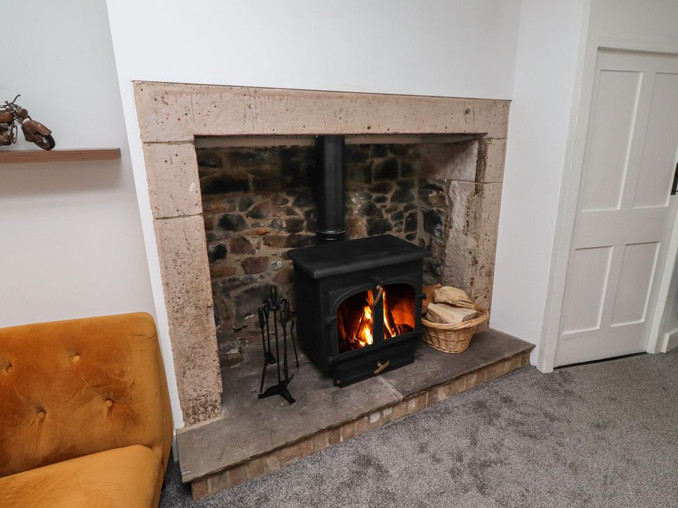 A living room with a fireplace and wood stove at 1 Sunnybrae in Alnwick