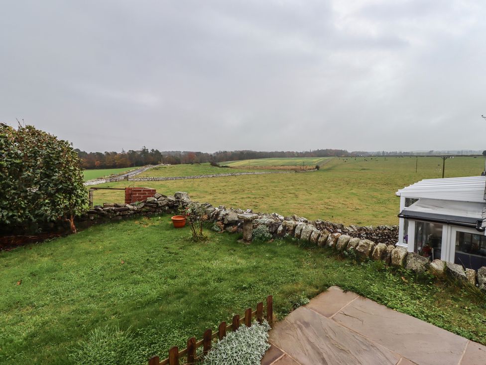 A garden with a stone wall and grass at 1 Sunnybrae in Alnwick