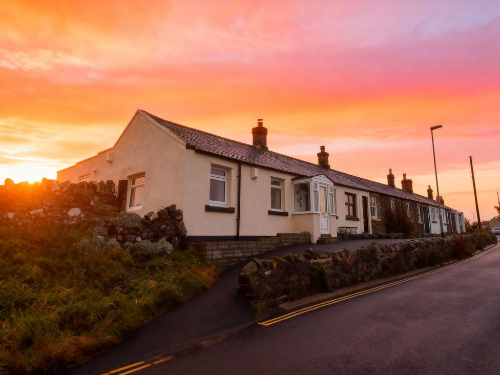 A house with a stone wall and road at 1 Sunny Brae in Embleton