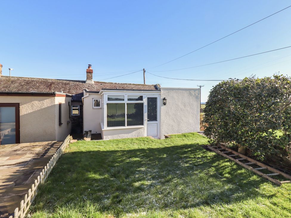 An outdoor view of a cottage with a door and window at Harry's Cottage in Embleton