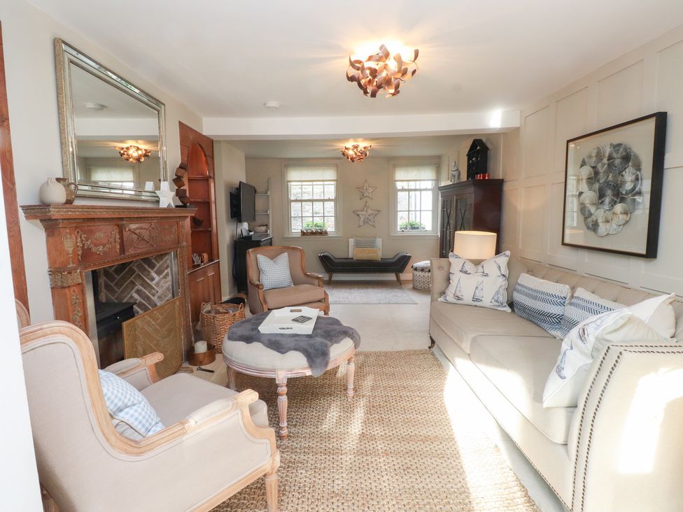 A living room with a sofa, armchair, and coffee table at The Music Box in Beaumaris