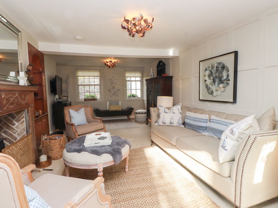 A living room with a sofa, armchair, and fireplace at The Music Box in Beaumaris