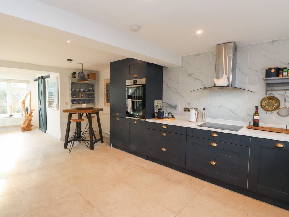 A kitchen with cabinets, stove, sink, and kitchen island at The Music Box in Beaumaris