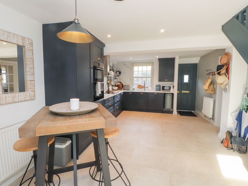 A kitchen with a dining table and stools at The Music Box in Beaumaris