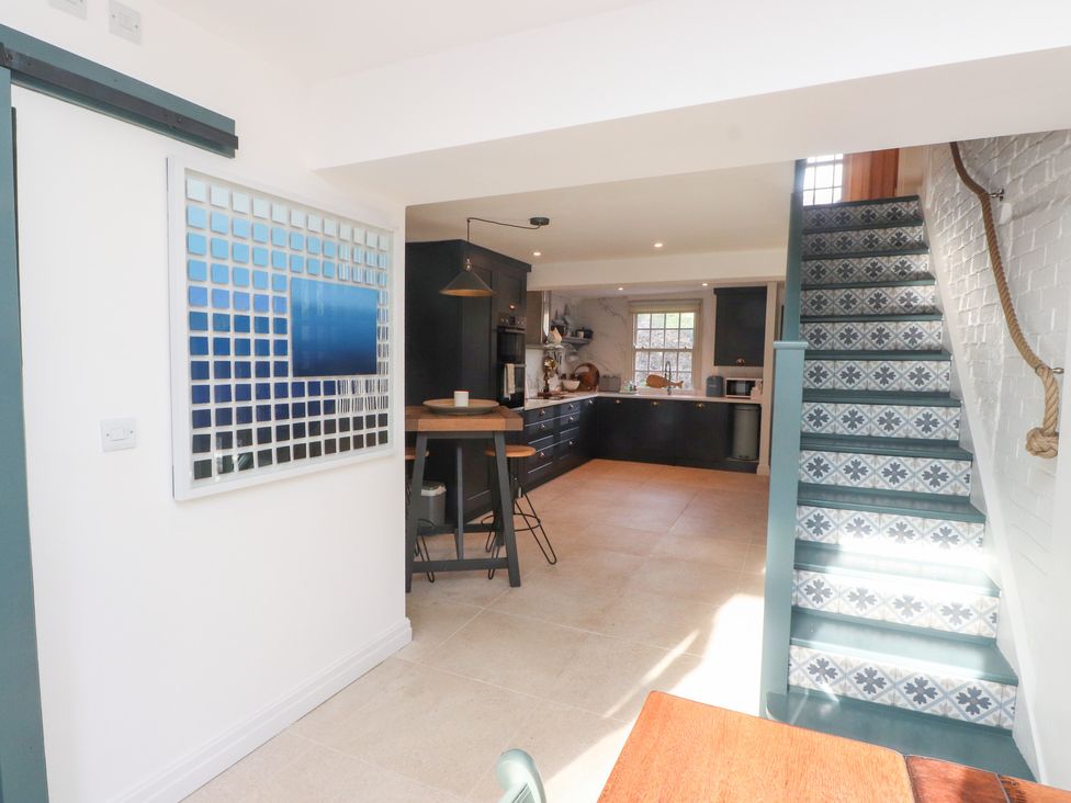 A kitchen with a staircase and dining area at The Music Box in Beaumaris