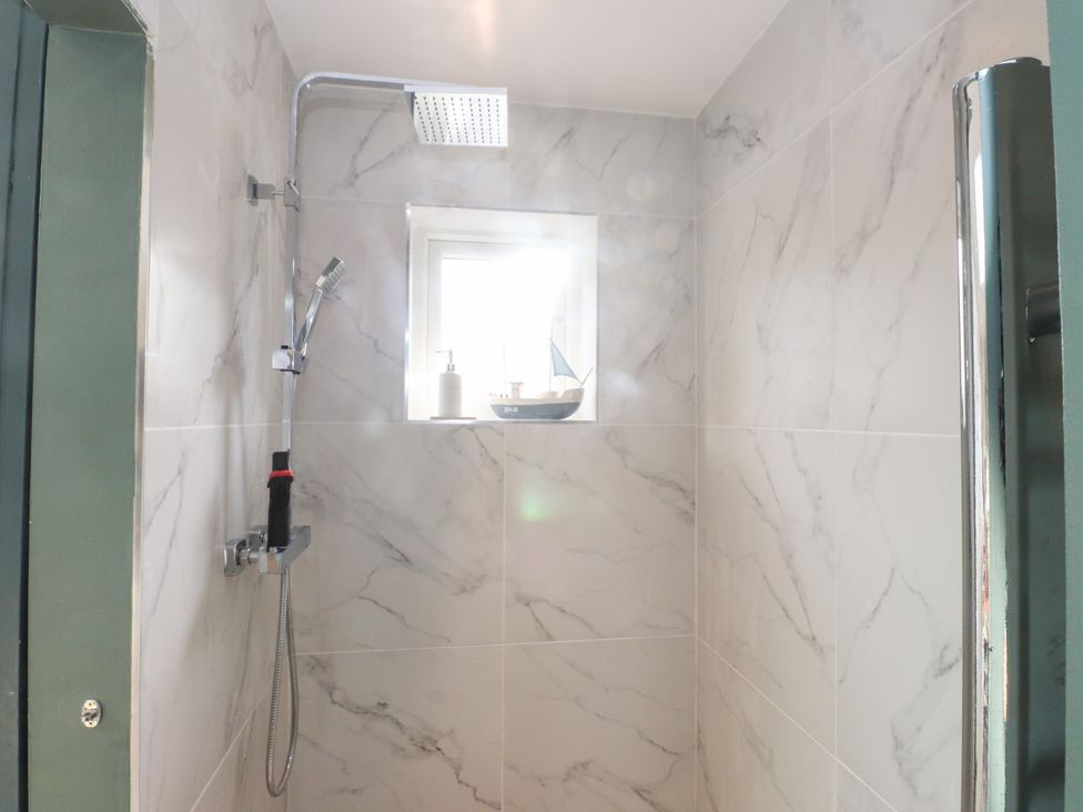 A shower with a window and soap dispenser at The Music Box Beaumaris