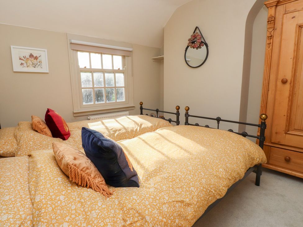 A bedroom with two beds and a wardrobe at The Music Box in Beaumaris