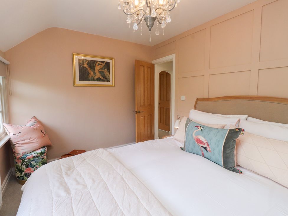 A bedroom with a bed, painting, and chair at The Music Box in Beaumaris