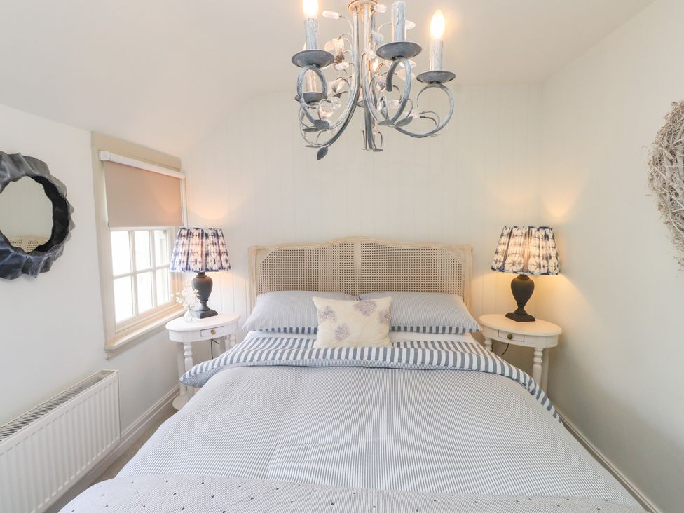 A bedroom with a bed, bedside tables and lamps at The Music Box in Beaumaris
