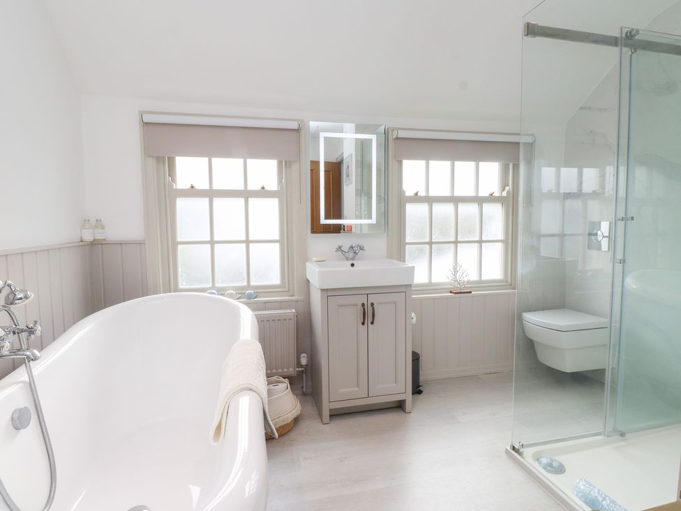 A bathroom with a bathtub, sink, and shower at The Music Box in Beaumaris