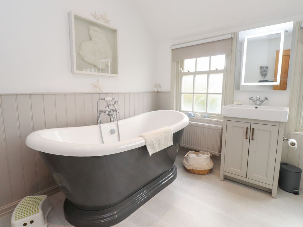A bathroom with a bathtub and washbasin at The Music Box in Beaumaris