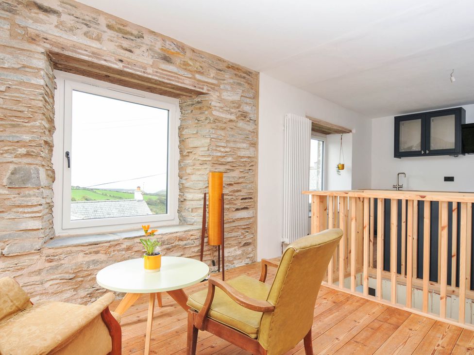 A living room featuring a table and chair with a plant at Boscabrea near Tintagel
