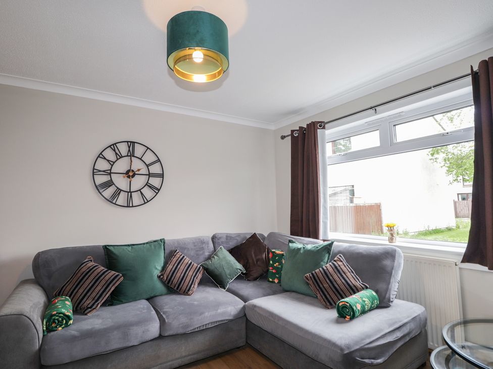 A living room with a sofa and clock at Clans Crescent Nairn