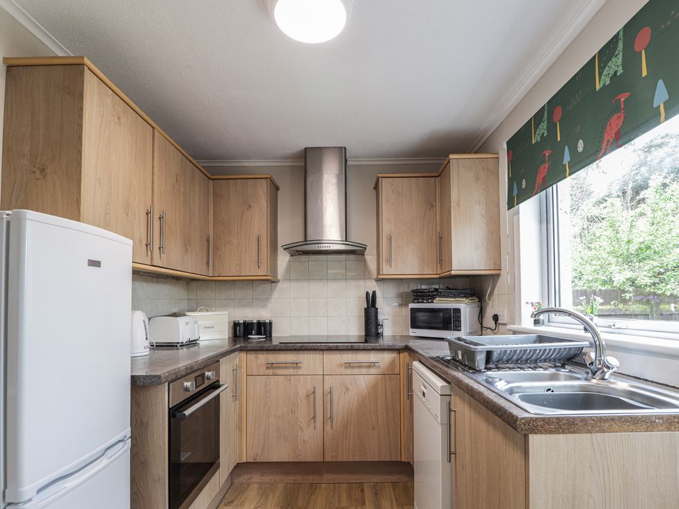 A kitchen with appliances and cabinetry at Clans Crescent Nairn