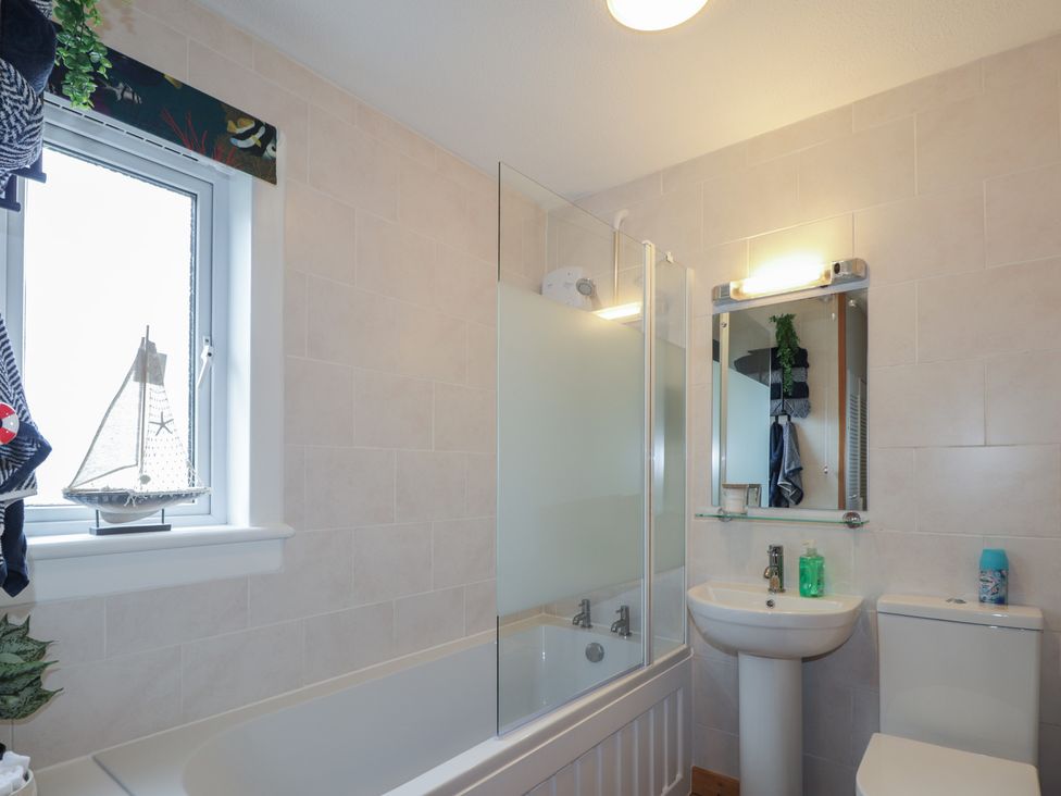 A bathroom with a bath tub, toilet, and sink at Clans Crescent in Nairn