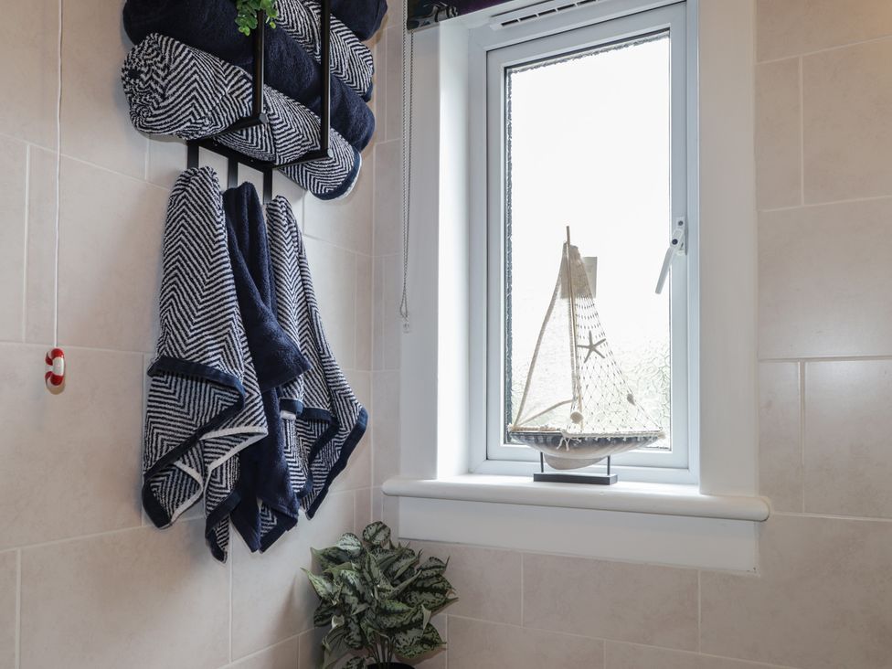 A bathroom with towels hanging, a window and a model sailboat at Clans Crescent Nairn