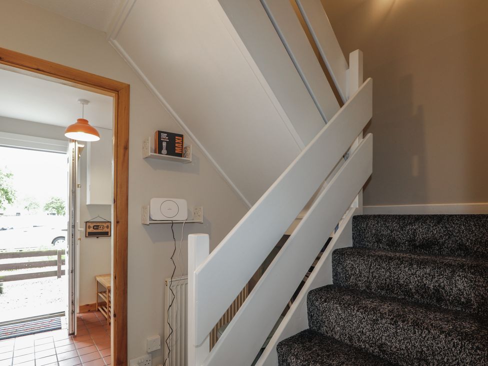 A hallway with stairs and door at Clans Crescent Nairn