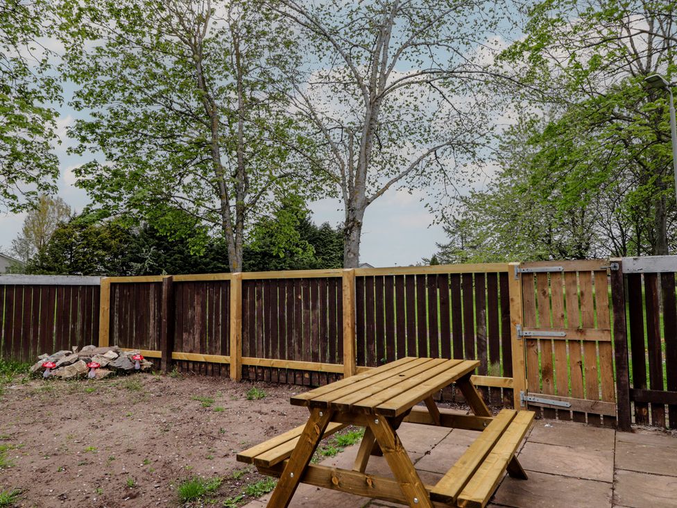 A picnic table and bench in a fenced area at Clans Crescent Nairn