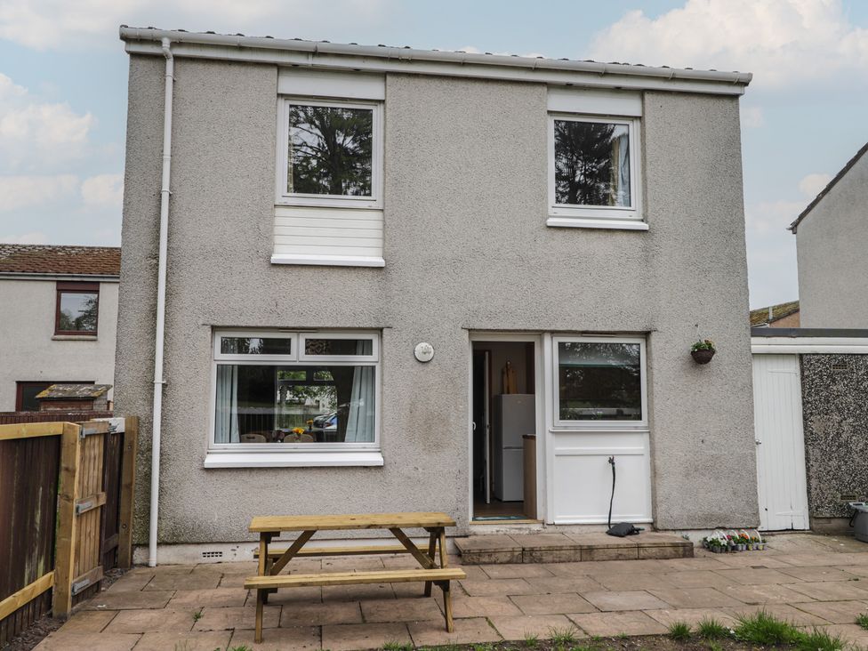 An exterior view of a house with a table and garden at Clans Crescent in Nairn