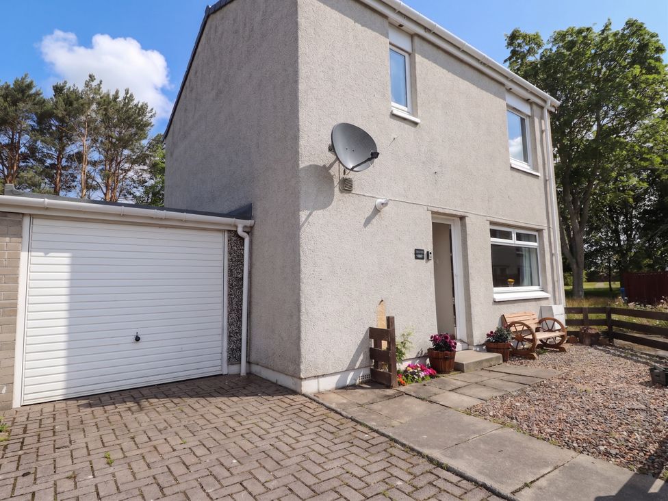 An outdoor view of a house with a garage and seating area at Taigh Ban in Nairn