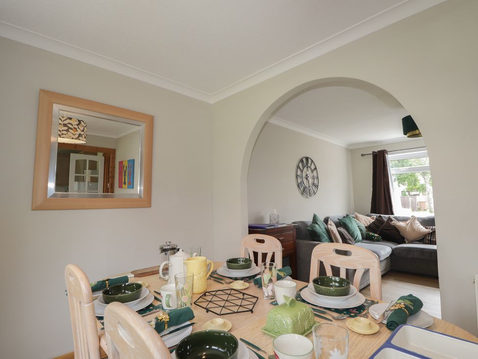 A dining room with a table set for meals and a view of a living room at Taigh Ban Nairn