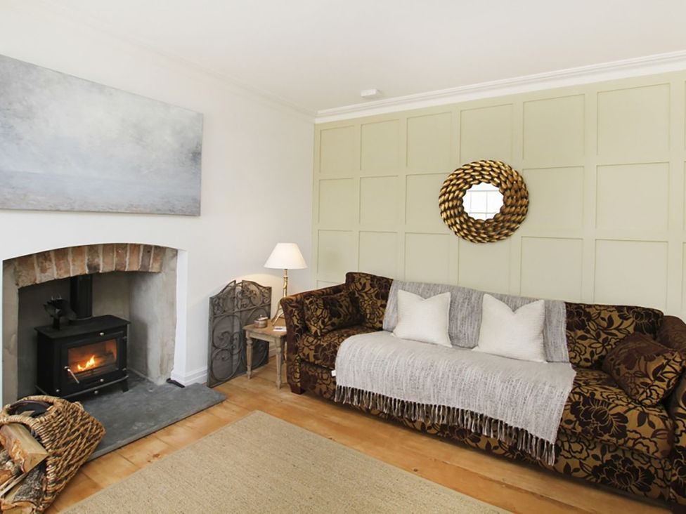 A living room with a sofa and a fireplace at Tri Raglan Bach in Beaumaris