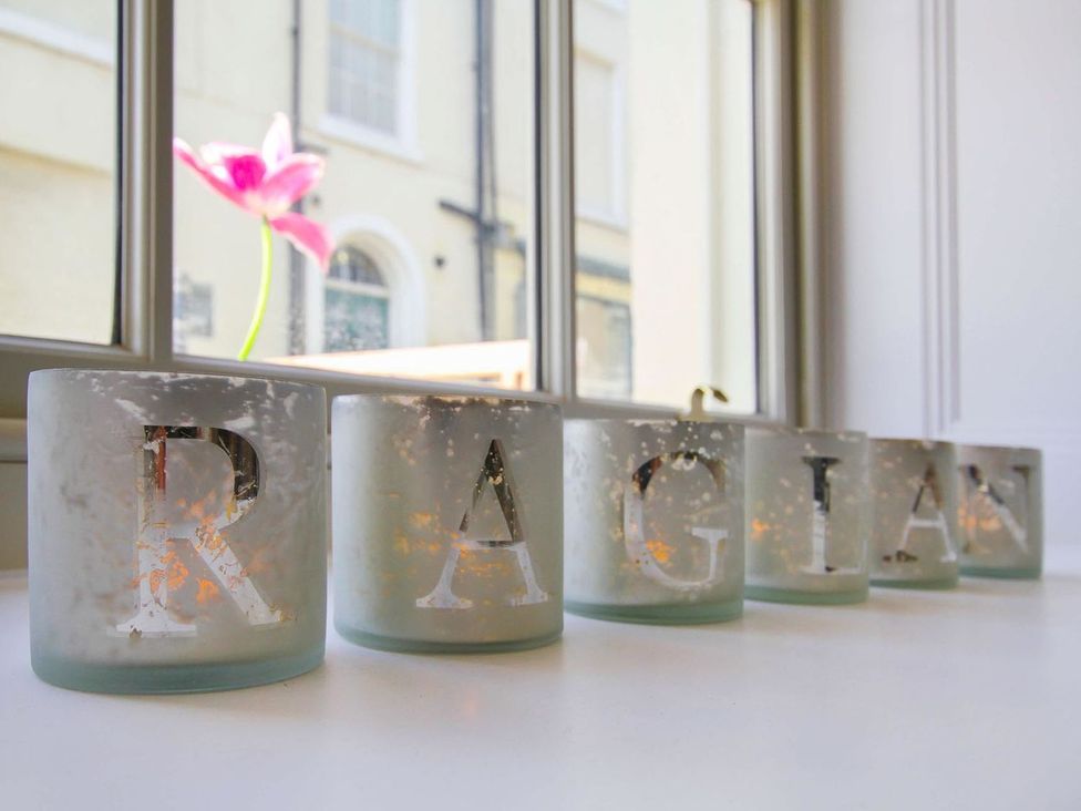 Candles arranged on table with a flower visible through the window at Tri Raglan Bach Beaumaris