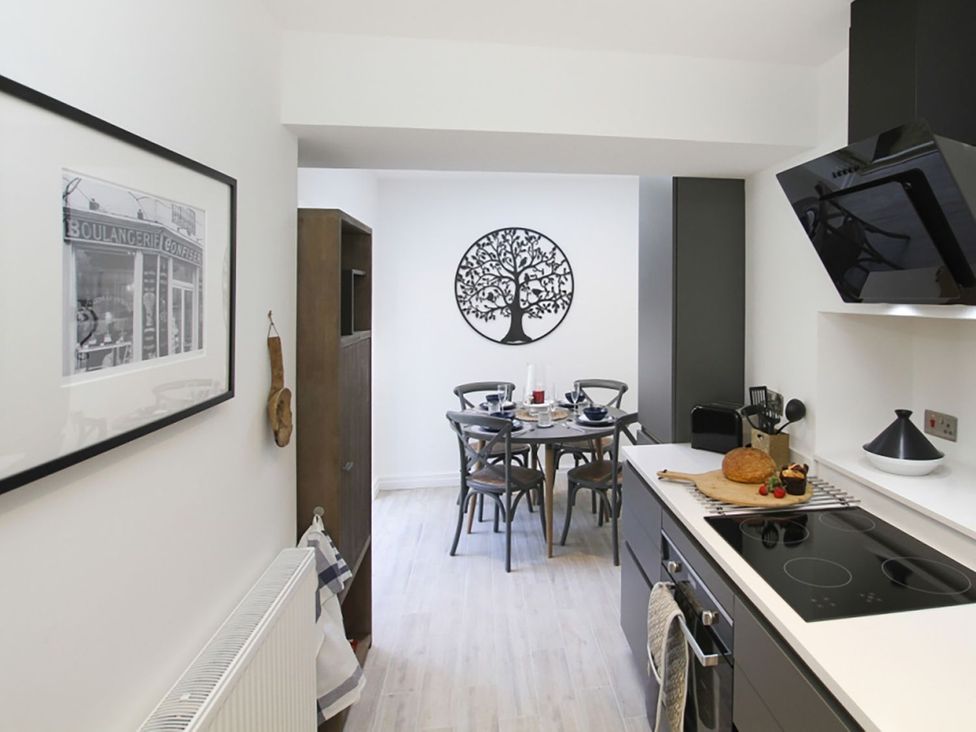 A kitchen with a dining table and chairs at Tri Raglan Bach Beaumaris