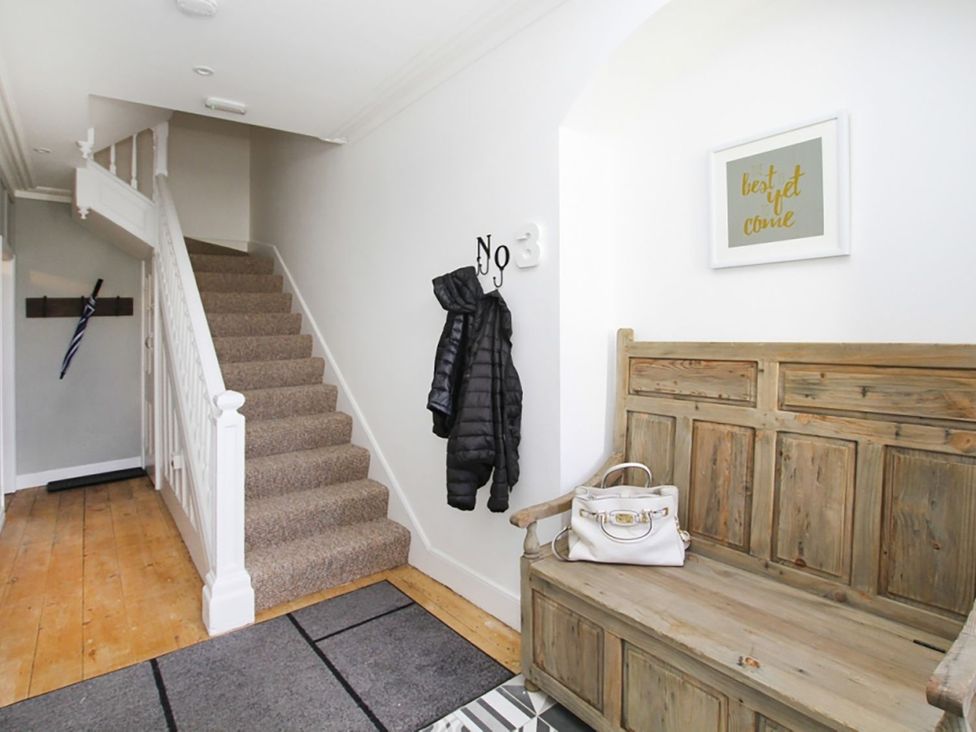 A hallway with a staircase and bench at Tri Raglan Bach Beaumaris