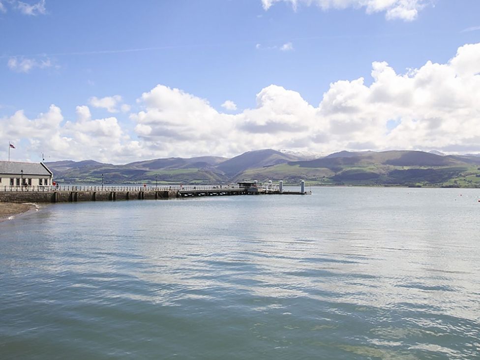 A pier extending into water with mountains in the background at Tri Raglan Bach Beaumaris