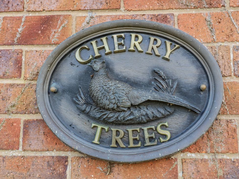 A nameplate with 'Cherry Trees' and a pheasant design on a brick wall