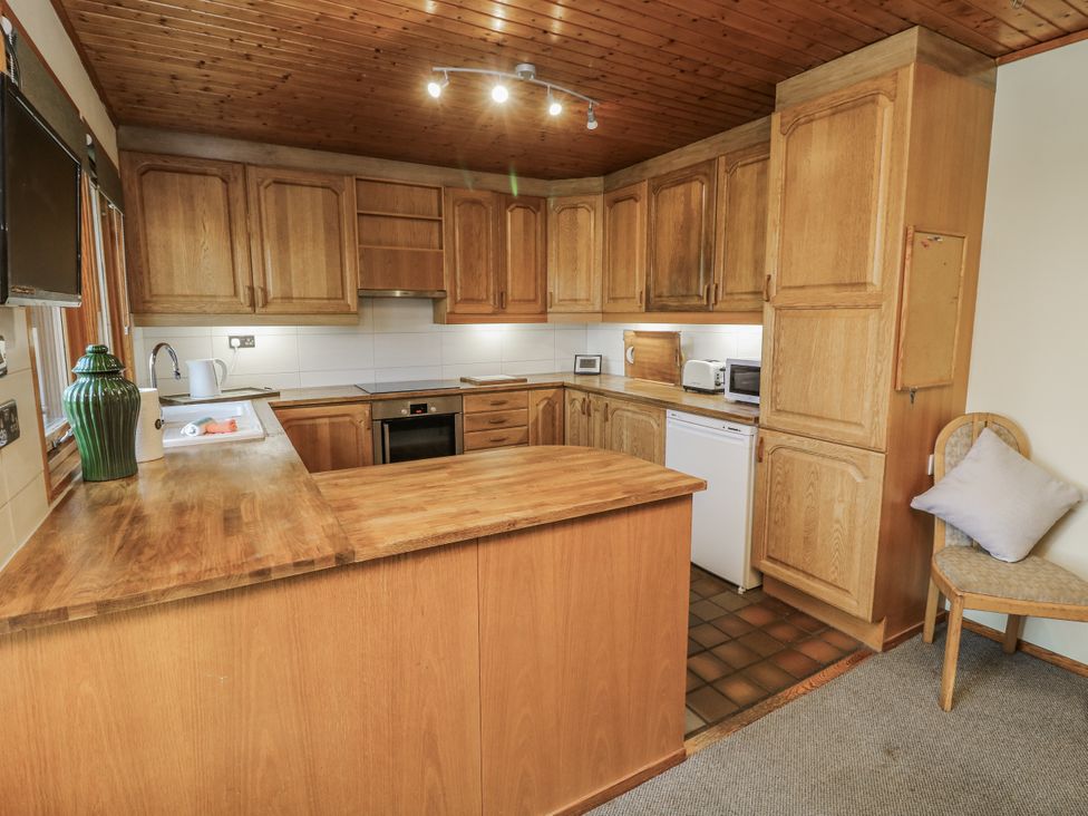 A kitchen with wooden cabinets and appliances at Cherry Trees 