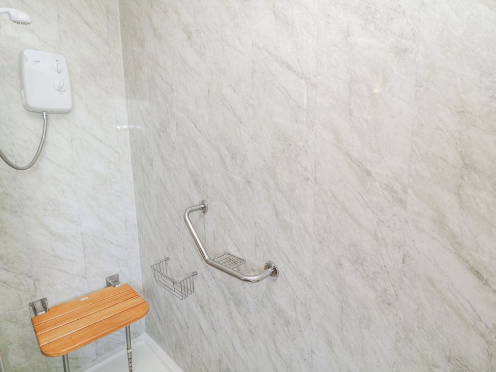 A shower area with a stool and grab bars at Cherry Trees