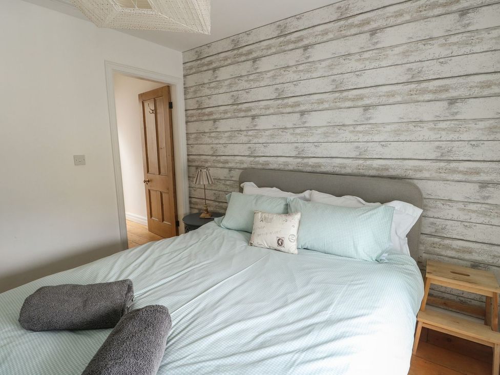 A bedroom with a bed, towels, and a lamp at Tri Raglan Mawr Beaumaris